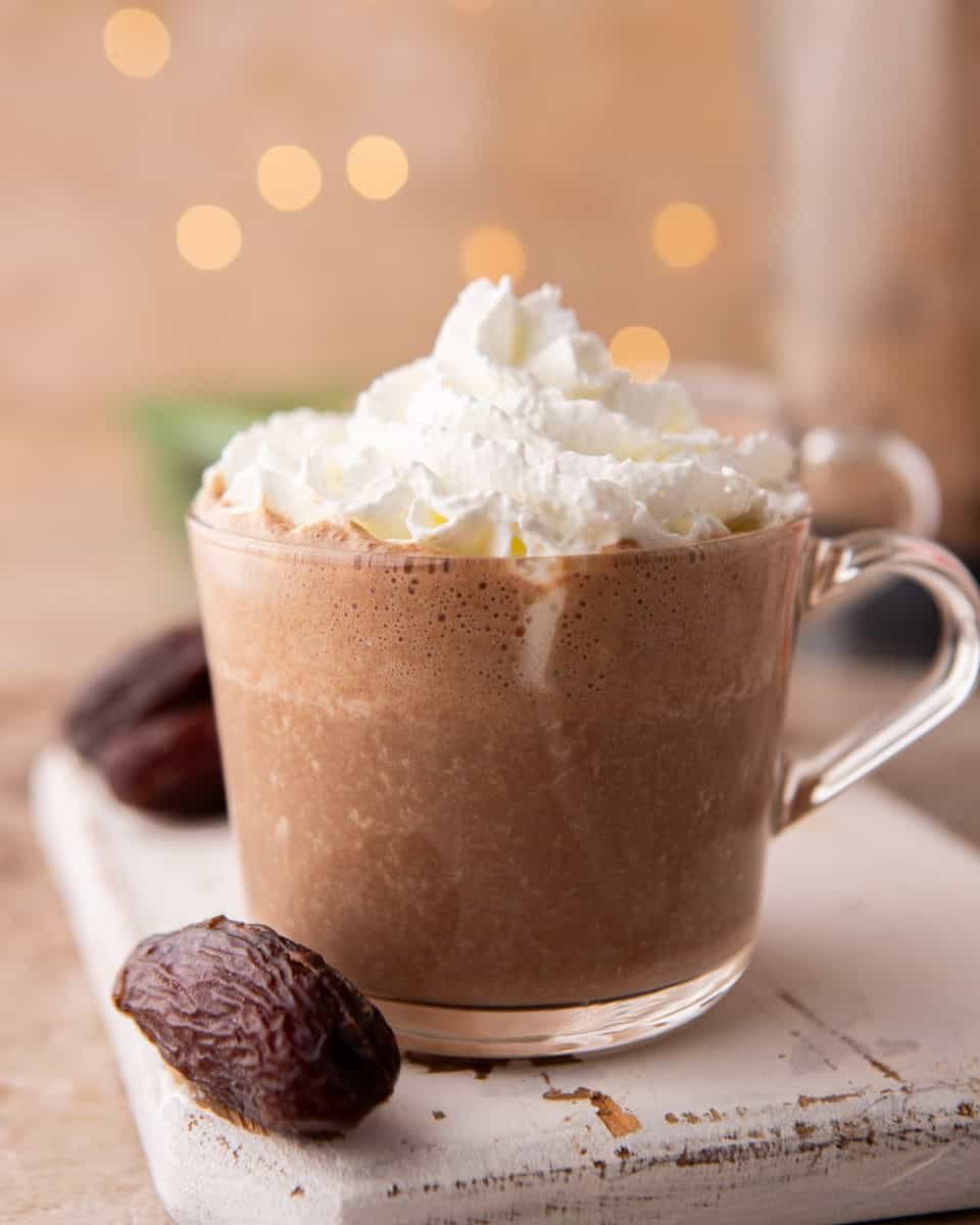 Date sweetened hot chocolate topped with whipped cream in a clear mug
