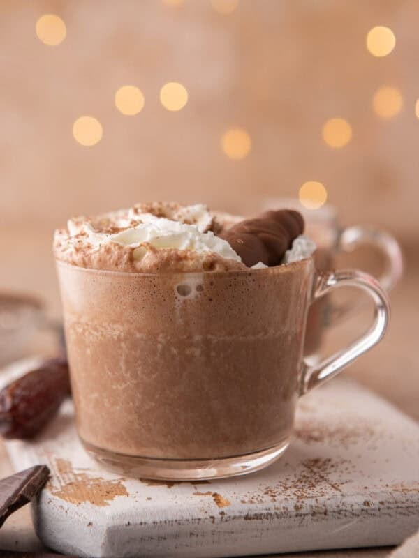 Date sweetened hot chocolate in a glass mug topped with whipped cream