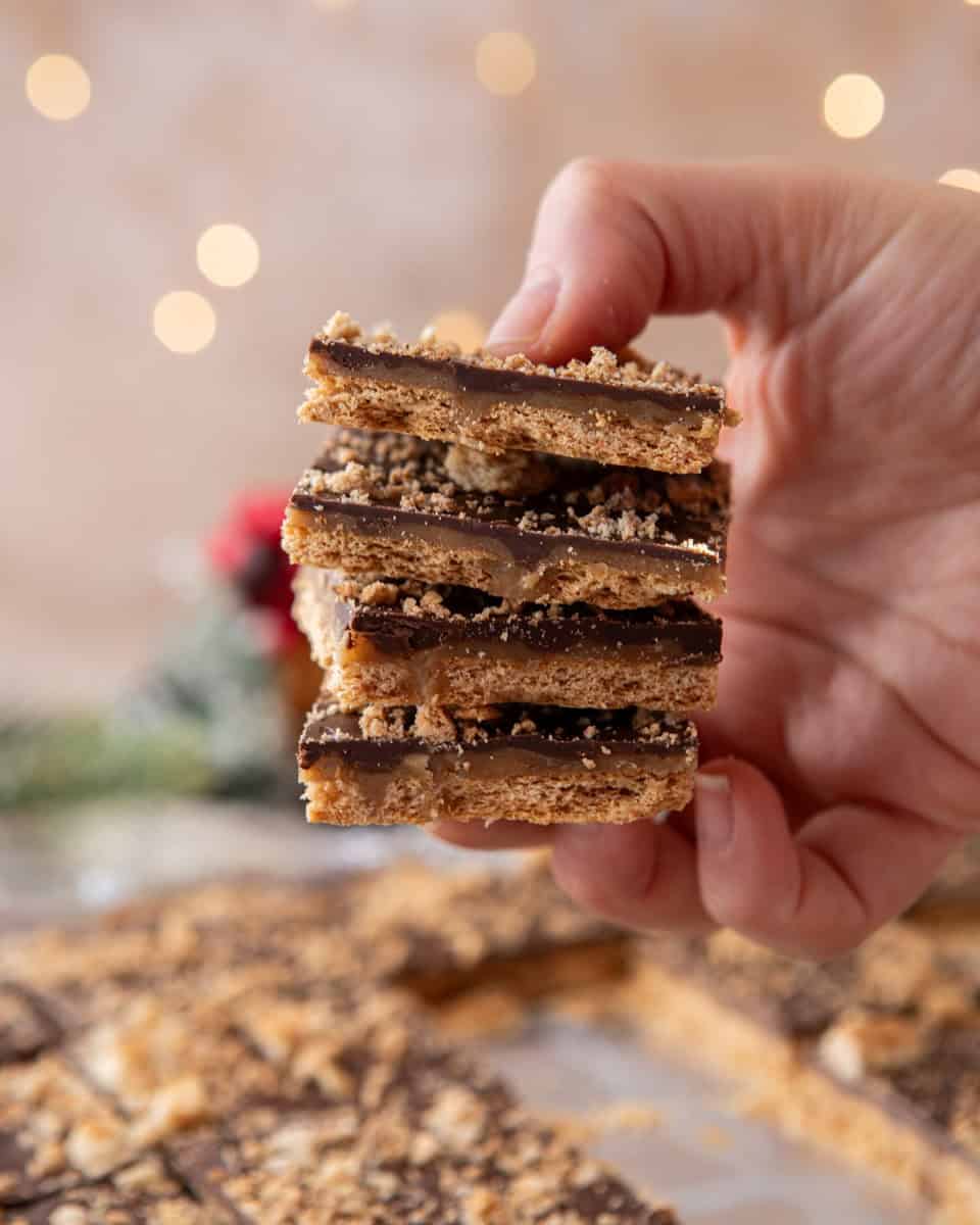 Hand holding stacked graham cracker Christmas crack pieces

