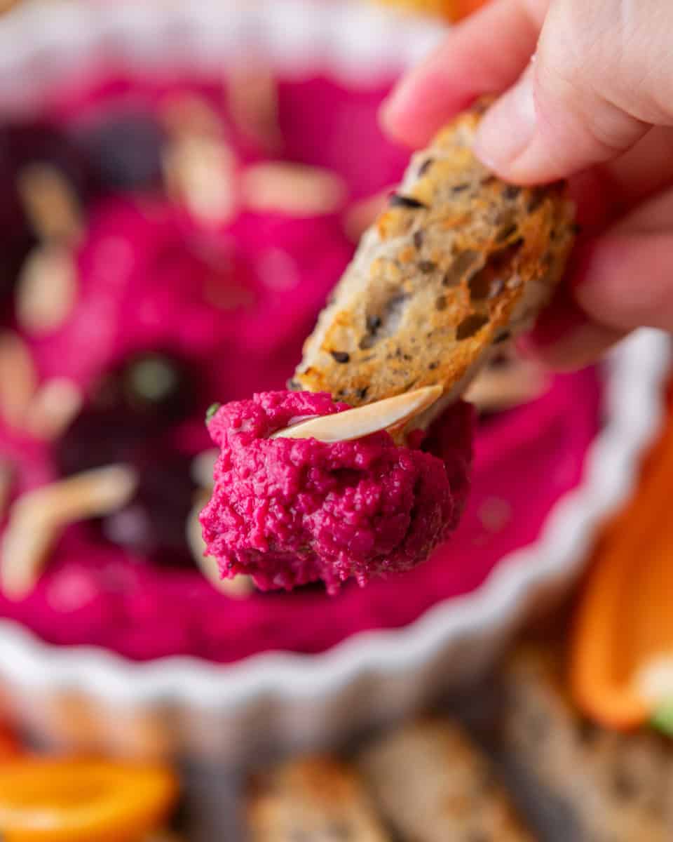 Crostini dipped into creamy beet hummus