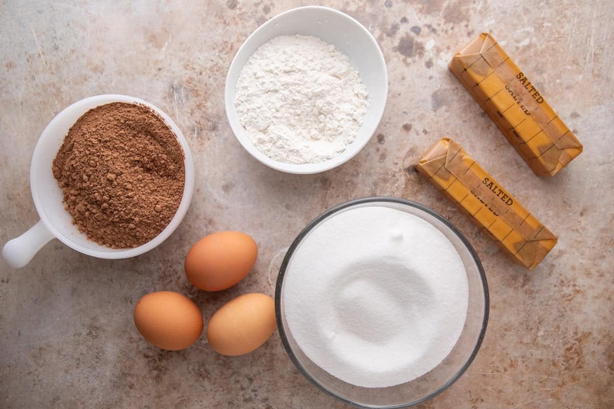 Ingredients for brownie pudding including eggs, cocoa powder, sugar, flour, and butter