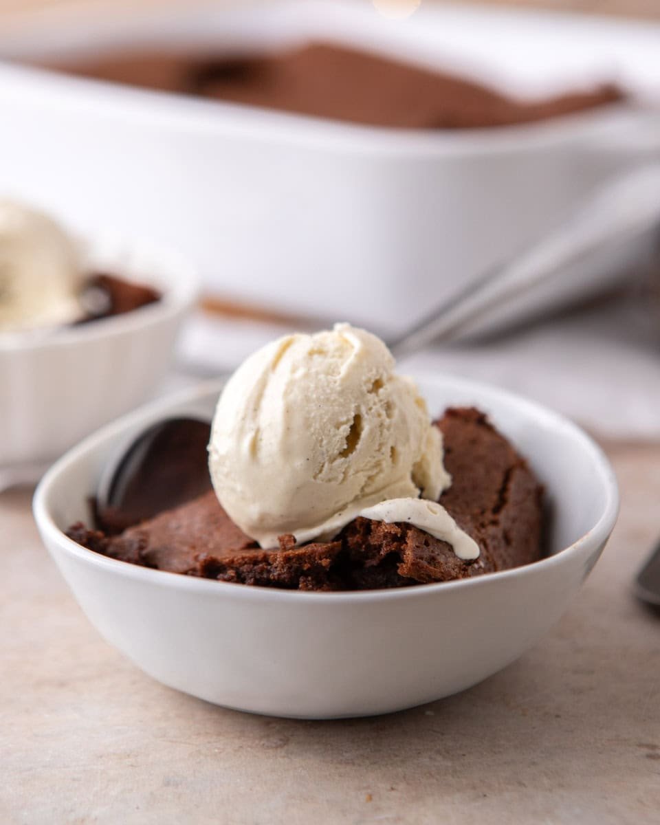 Brownie pudding served warm with vanilla ice cream in a white bowl