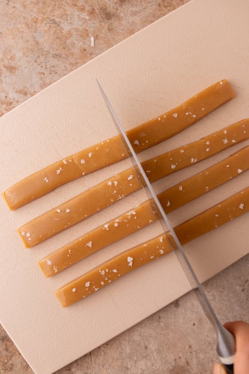 Cutting cooled caramel slab into strips using a sharp knife
