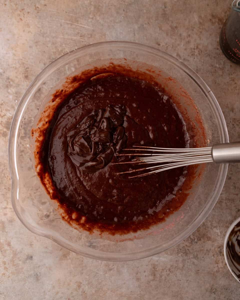 Smooth chocolate cake batter being whisked in a bowl
