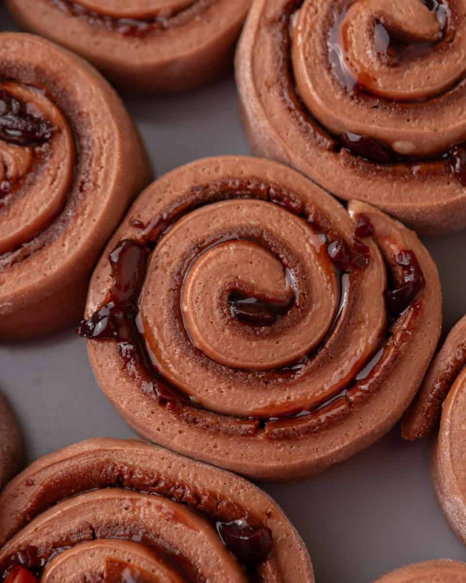 Close-up of chocolate cinnamon rolls with visible cherry filling
