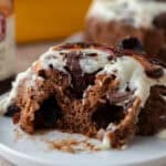Soft Black Forest cinnamon roll with chocolate dough, cherry filling, and vanilla mascarpone frosting on a plate