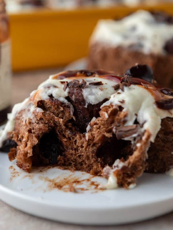 Soft Black Forest cinnamon roll with chocolate dough, cherry filling, and vanilla mascarpone frosting on a plate