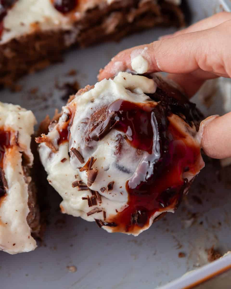 Cherry chocolate cinnamon roll pulled apart with mascarpone frosting and cherry sauce