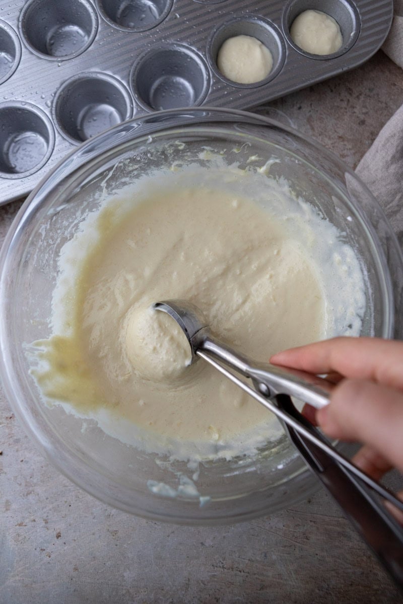 Scooping Brazilian cheese bread batter into mini muffin pan