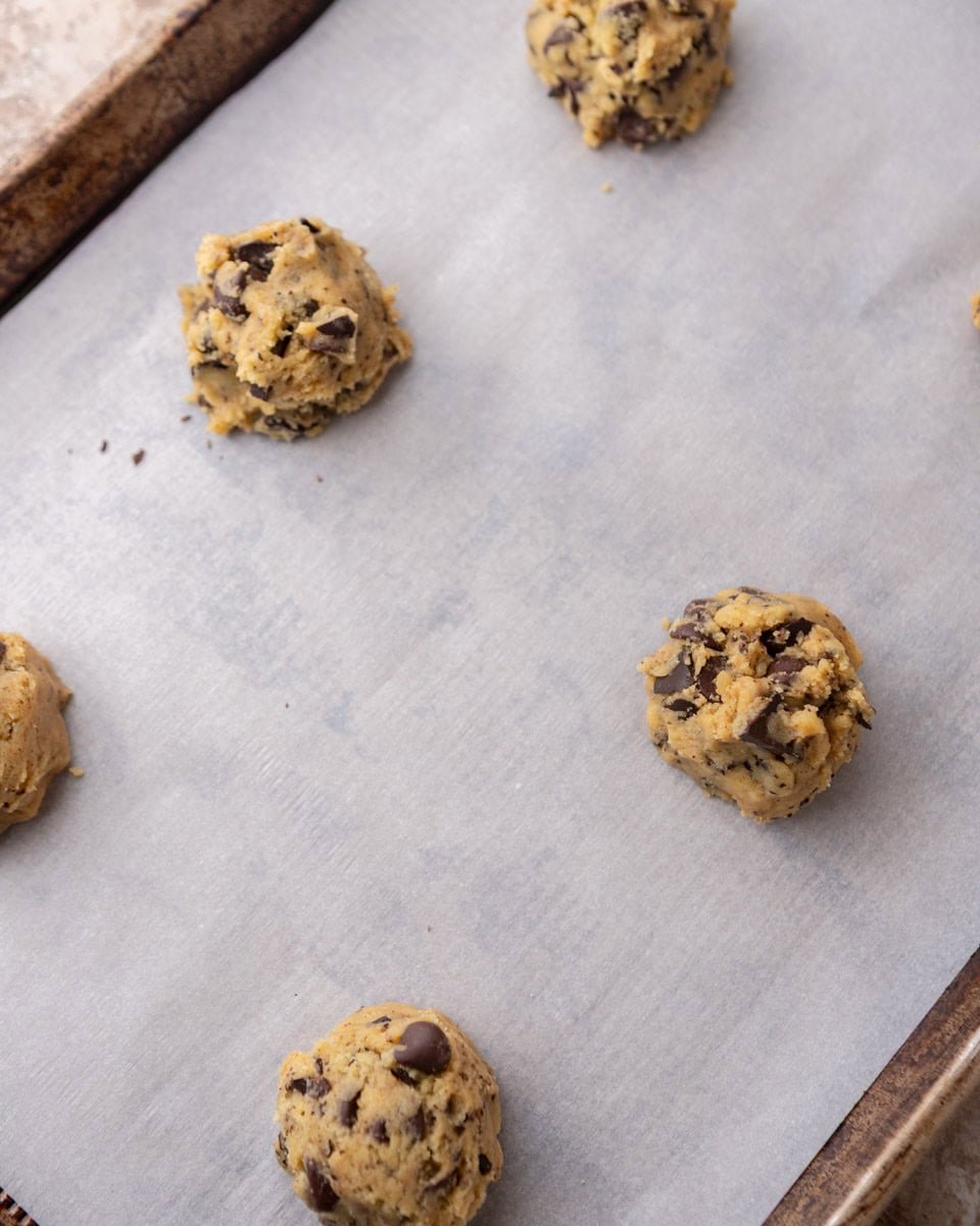 Cream cheese cookie dough balls on parchment-lined baking sheet