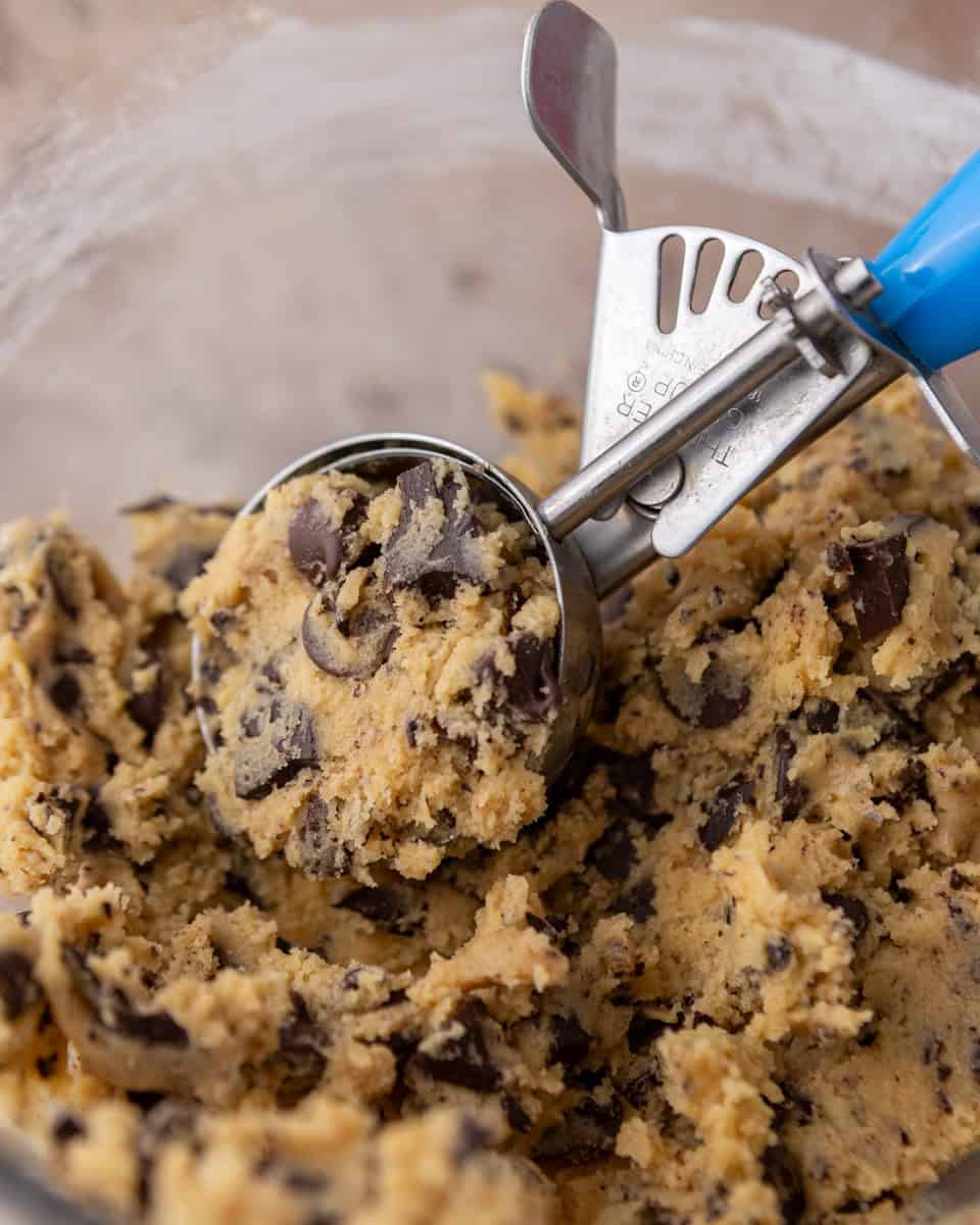 Scooping cream cheese chocolate chip cookie dough with a cookie scoop
