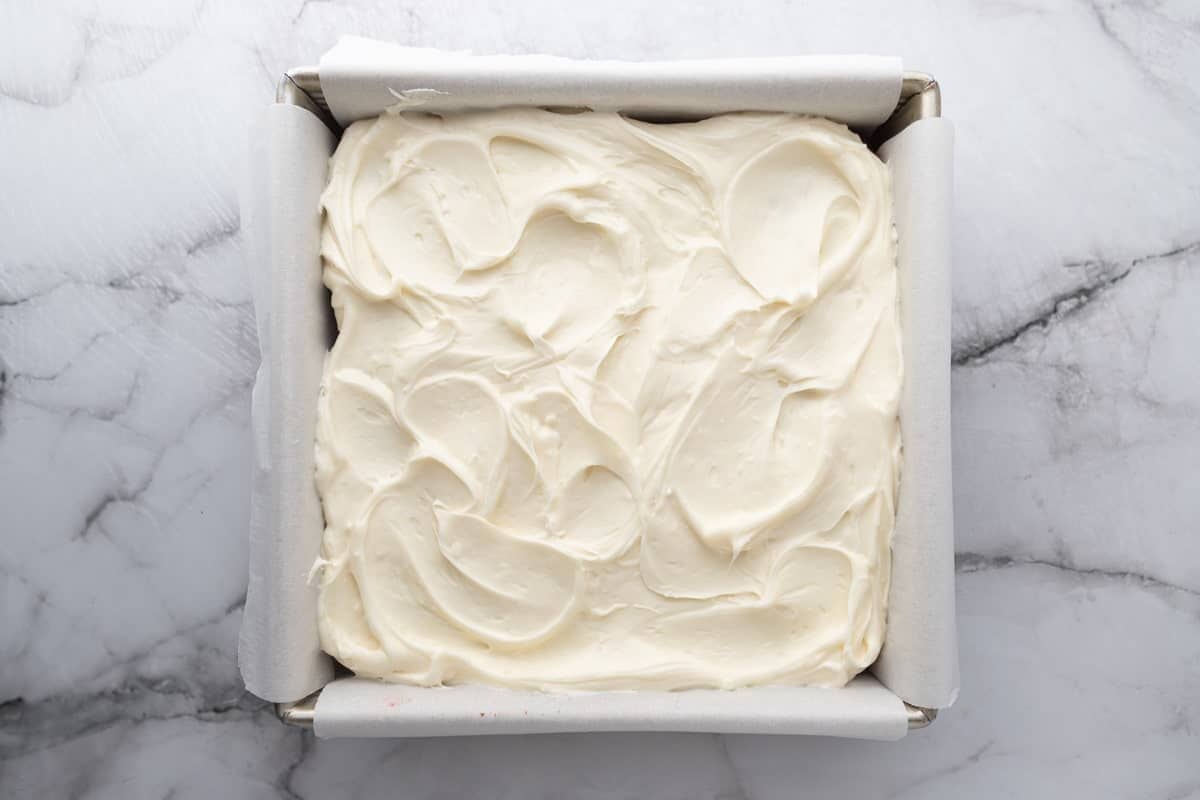 cream cheese frosting spread over the baked snack cake