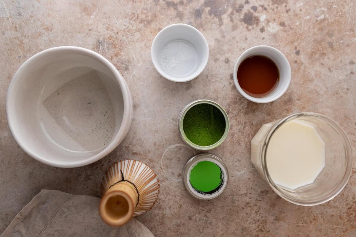 Ingredients for a salted maple matcha latte laid out on a counter