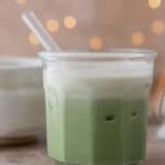 Iced salted matcha latte with a cream top and flickering lights behind it.