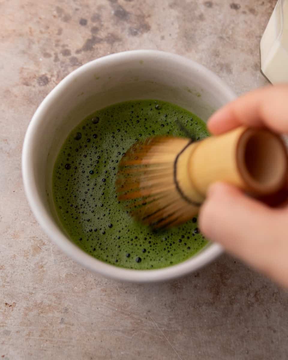 Whisked matcha being mixed until smooth and foamy