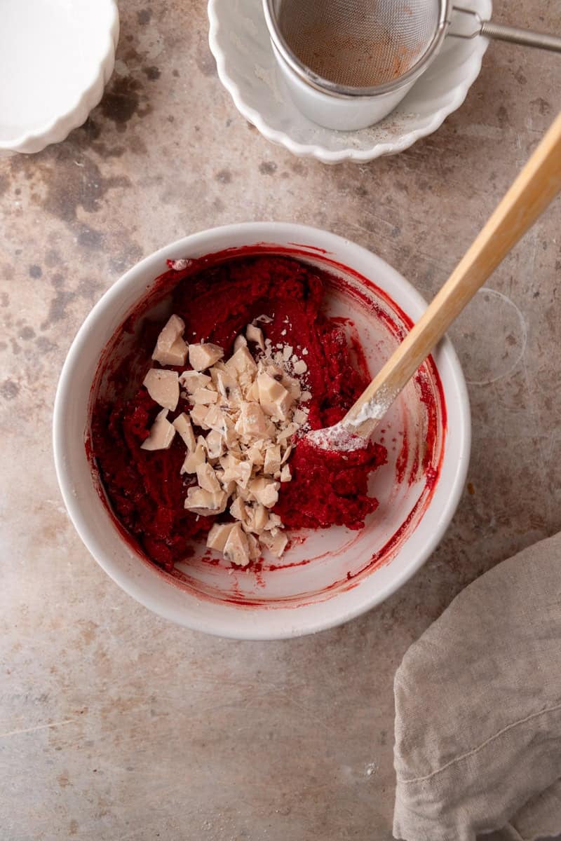 White chocolate chunks folded into red velvet cookie dough