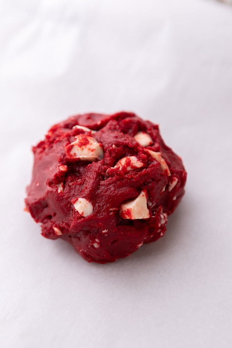 Unbaked single serve red velvet cookie dough on parchment paper