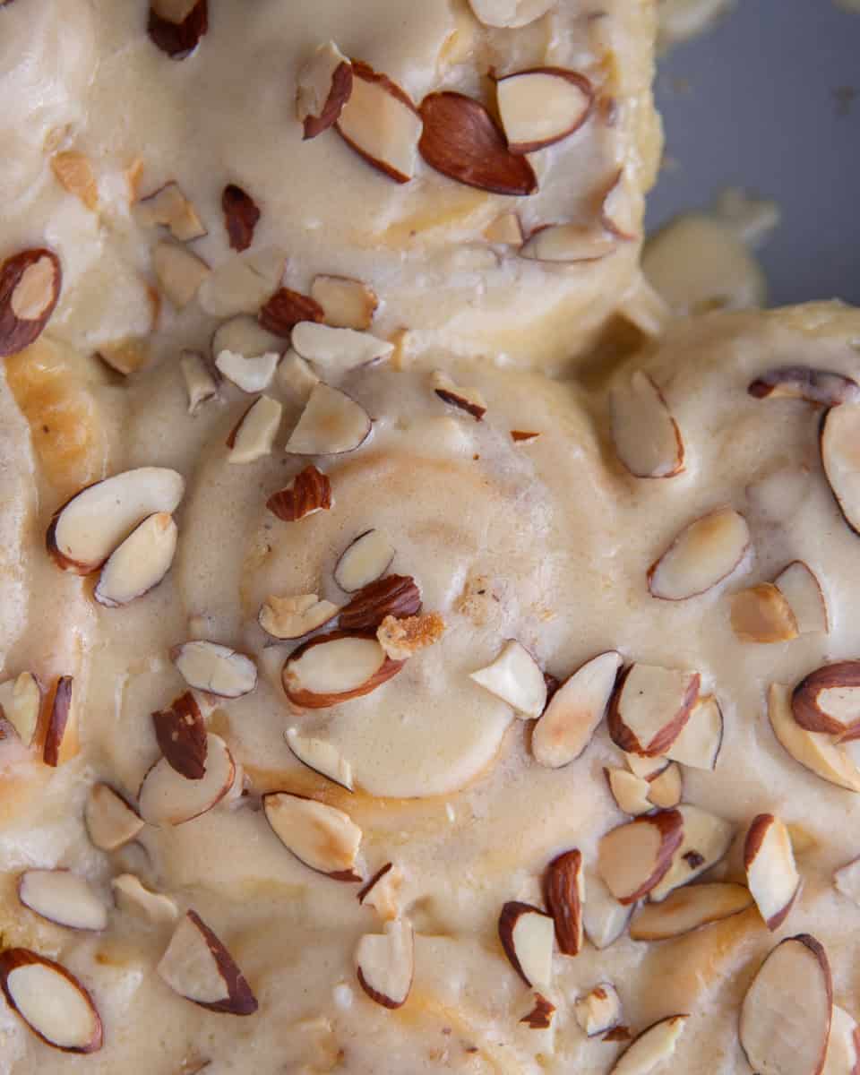 Almond glaze drizzled over warm cinnamon rolls