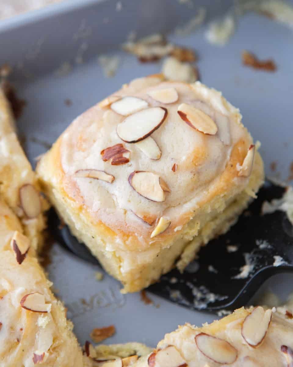 Almond croissant cinnamon roll topped with glaze and toasted sliced almonds