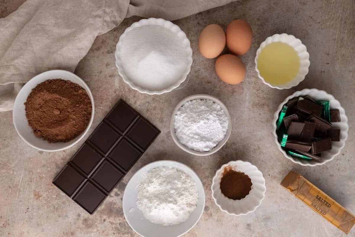 Brownie ingredients arranged on a countertop including cocoa powder, eggs, flour, and chocolate
