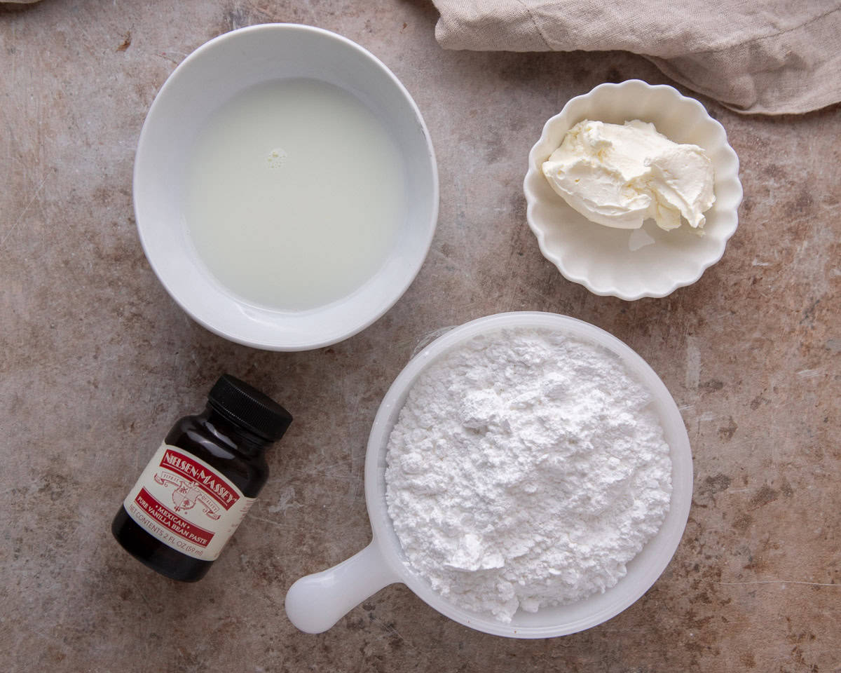 Ingredients for vanilla cream cheese glaze including powdered sugar, cream cheese, milk, and vanilla extract.