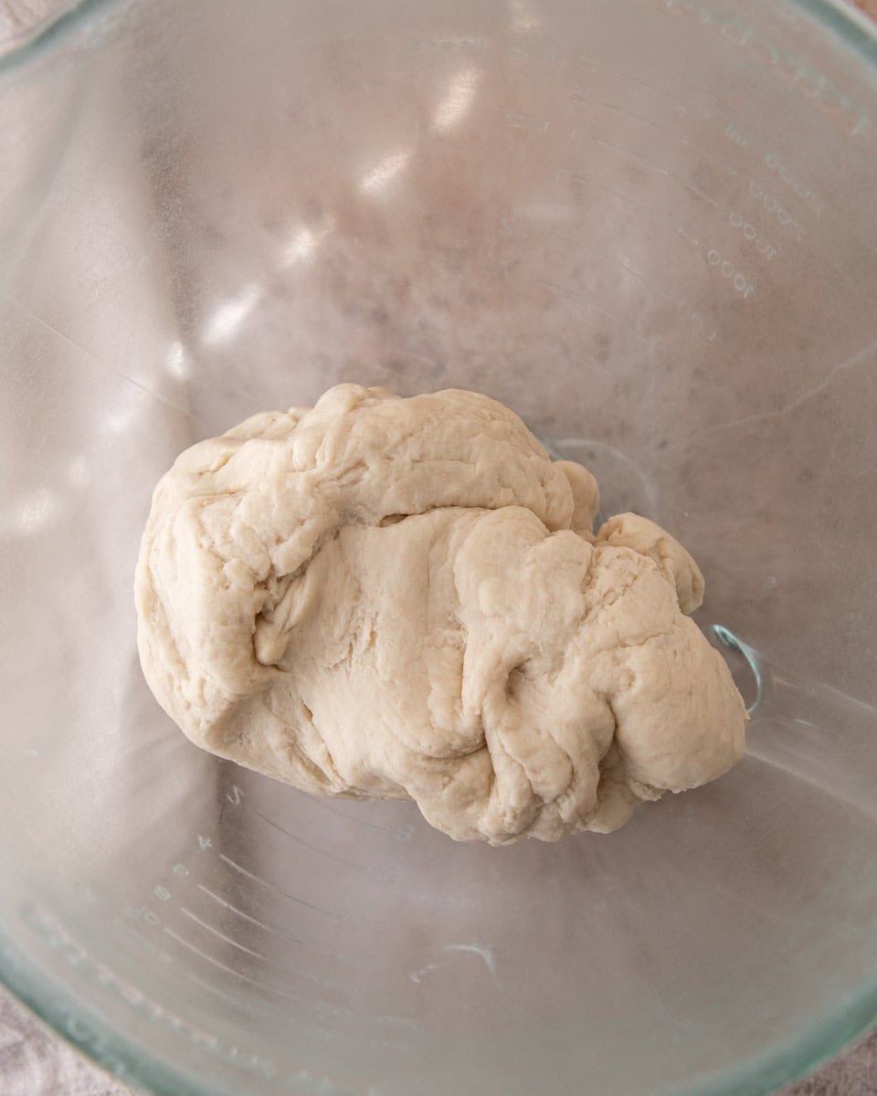 Shaggy enriched croissant dough in a glass mixing bowl before resting