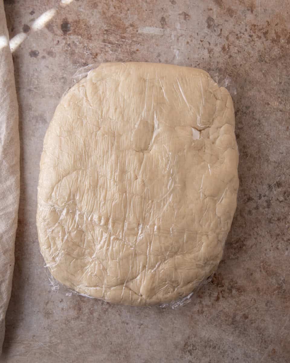 Croissant dough shaped into a rectangle and wrapped in plastic wrap for chilling
