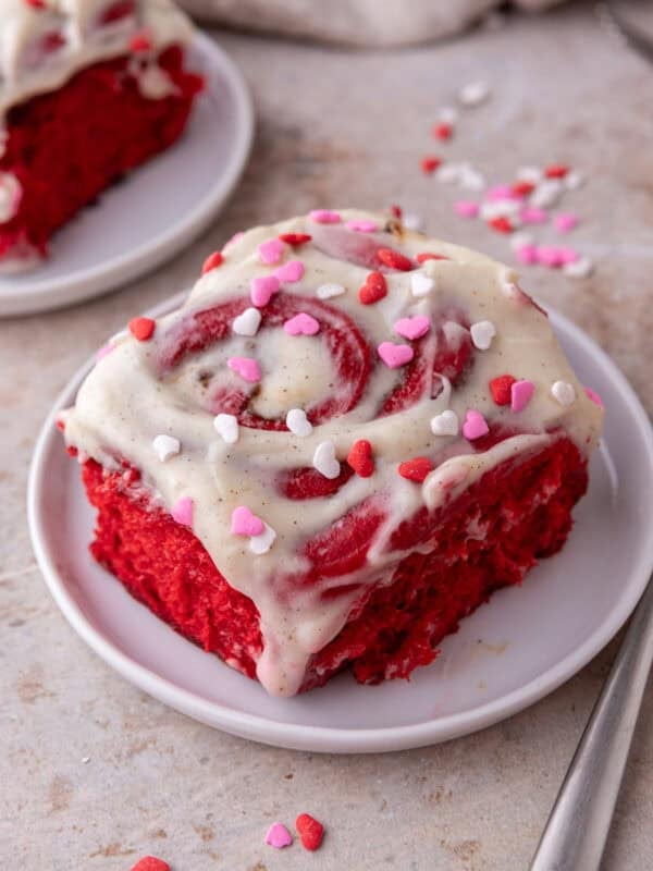 Close up of red velvet cinnamon rolls with cream cheese frosting and heart sprinkles
