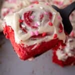 Soft red velvet cinnamon roll lifted from the pan showing the fluffy texture