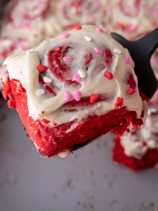 Soft red velvet cinnamon roll lifted from the pan showing the fluffy texture