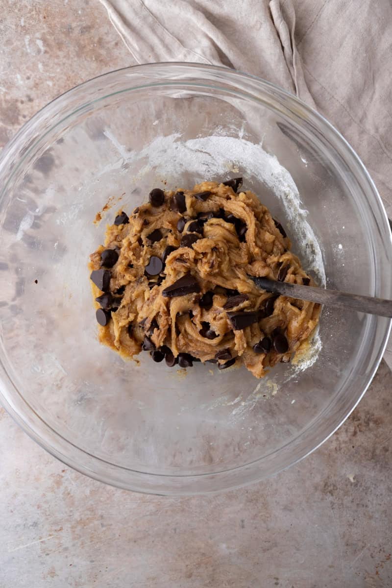 Overhead of dough with chocolate chips and chopped chocolate folded in, ready to press into a cast iron skillet