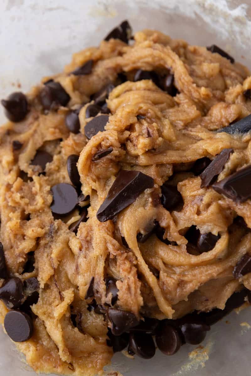 Close-up of thick cookie dough showing the rich golden color from brown butter and a mix of chocolate chips and chopped dark chocolate