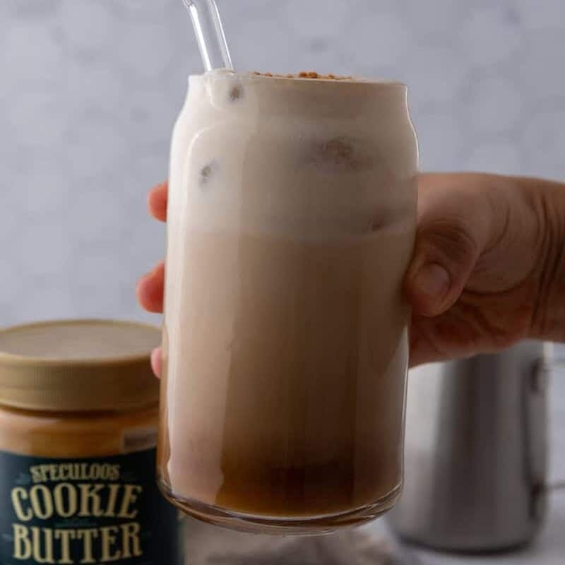 hand holding cup of cookie butter latte showing the different layers of the drink