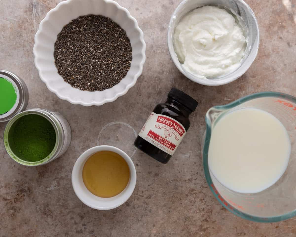 Ingredients needed to make matcha chia pudding including chia seeds, Greek yogurt, milk, maple syrup, vanilla, and matcha powder