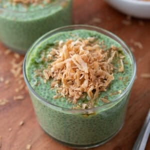 Matcha chia pudding topped with toasted coconut in a glass bowl