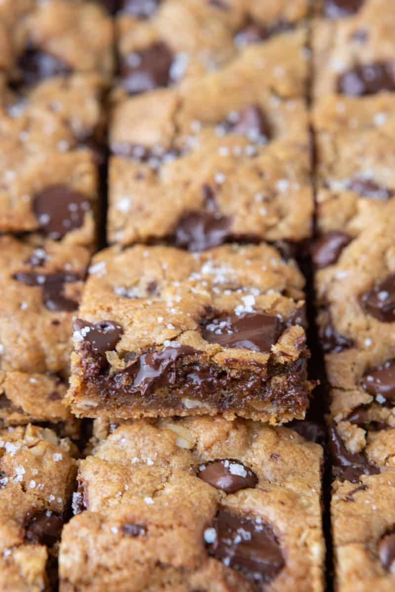 Close up of sliced chewy cookie bars with one tilted to show the gooey chocolate center and soft interior