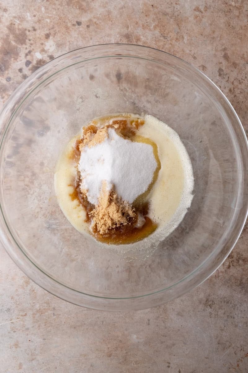 Brown butter with brown sugar and granulated sugar in a glass mixing bowl before whisking