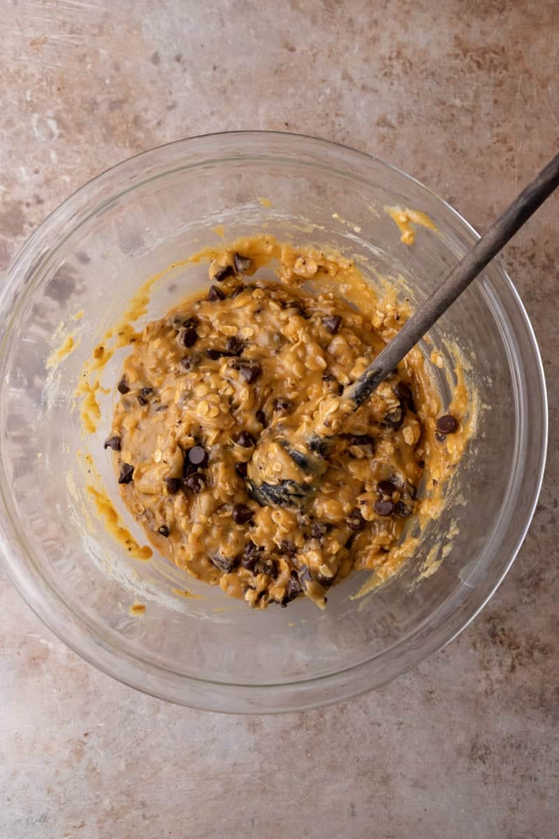 Freshly baked oatmeal cookie bar slab in a parchment-lined 8x8 baking pan topped with flaky salt