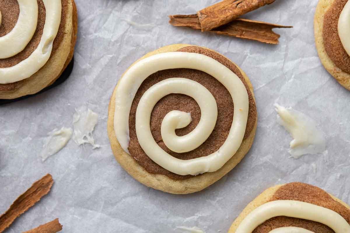 Crumbl cinnamon swirl cookie with cream cheese frosting spiral on parchment paper