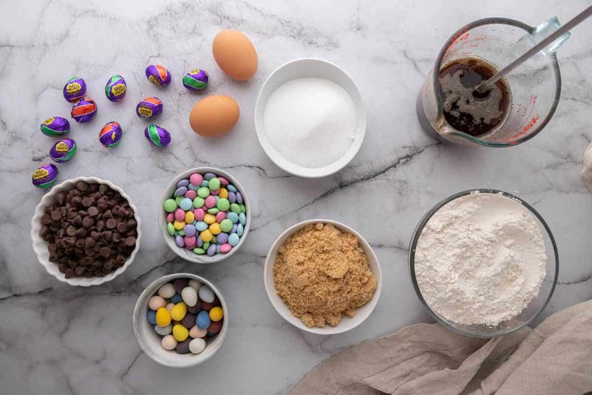 Ingredients including flour, eggs, chocolate chips, mini eggs, and M&M candies