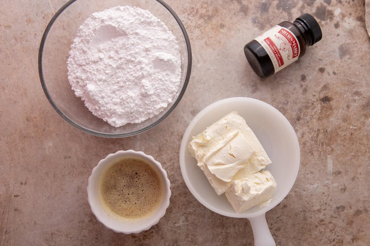 Ingredients for brown butter cream cheese frosting including powdered sugar, cream cheese, browned butter, and vanilla extract