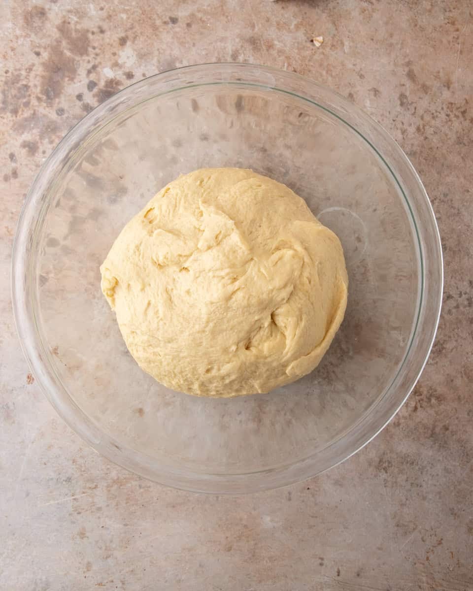 Smooth ball of tangzhong brioche dough in a glass bowl before the first rise