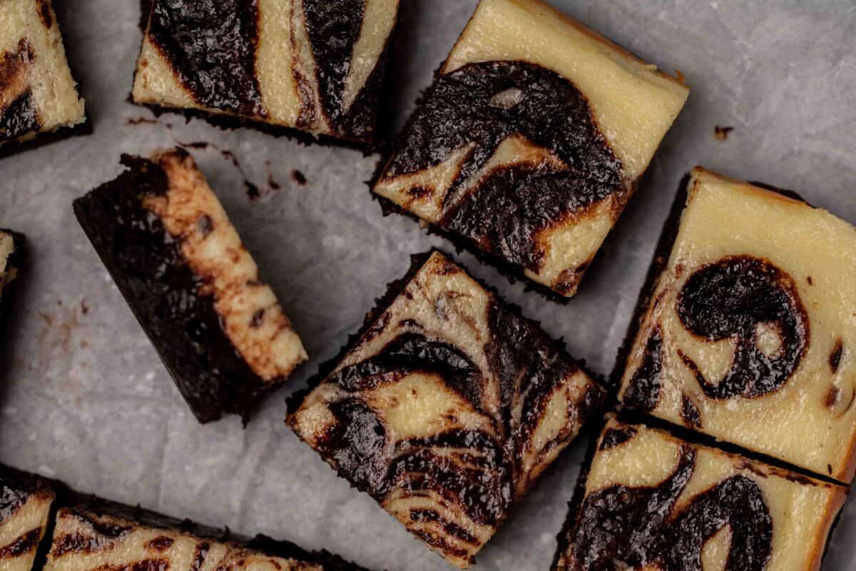 Cream cheese cheesecake brownies sliced into squares showing the marbled swirl pattern of tangy cream cheese and fudgy chocolate brownie with one piece tilted on its side