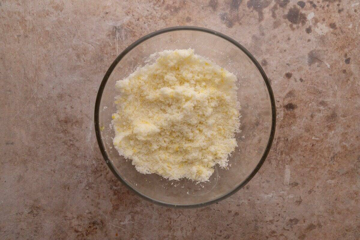 Lemon zest rubbed into granulated sugar in a glass bowl for lemon roll filling