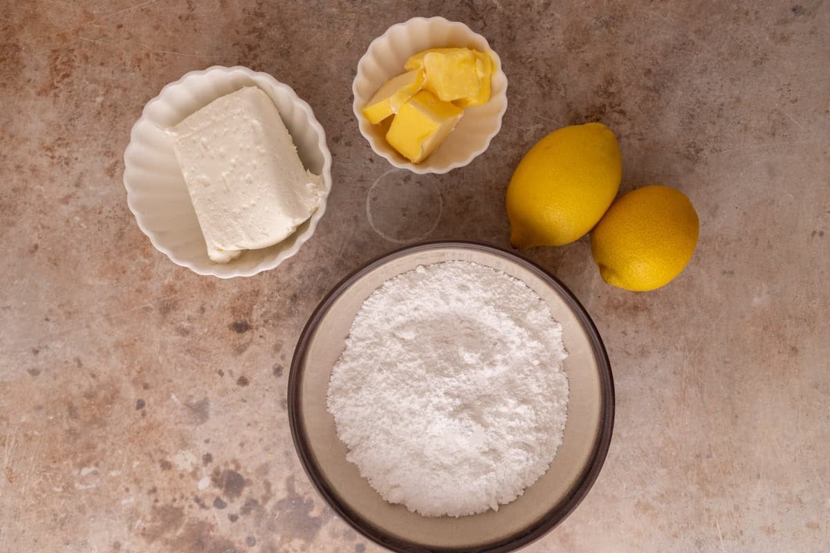 Cream cheese frosting ingredients including cream cheese, butter, powdered sugar and lemons