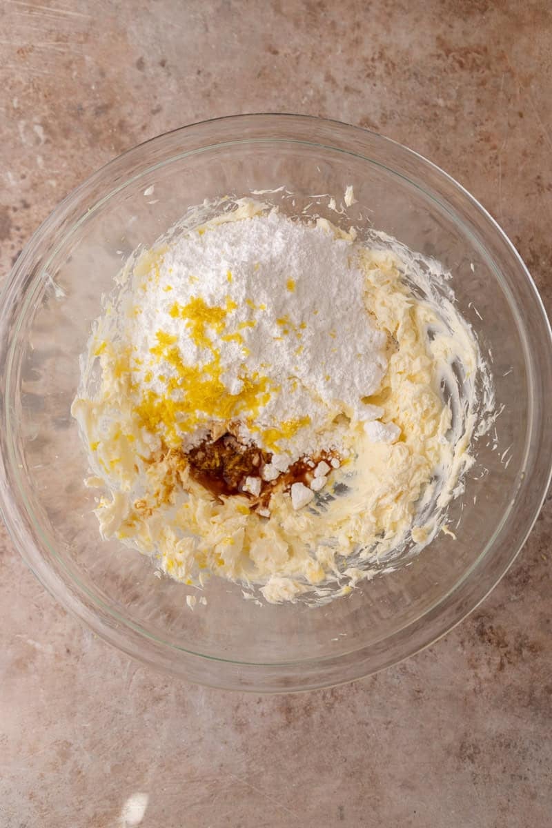Cream cheese and butter with powdered sugar, lemon zest and vanilla before mixing in a glass bowl