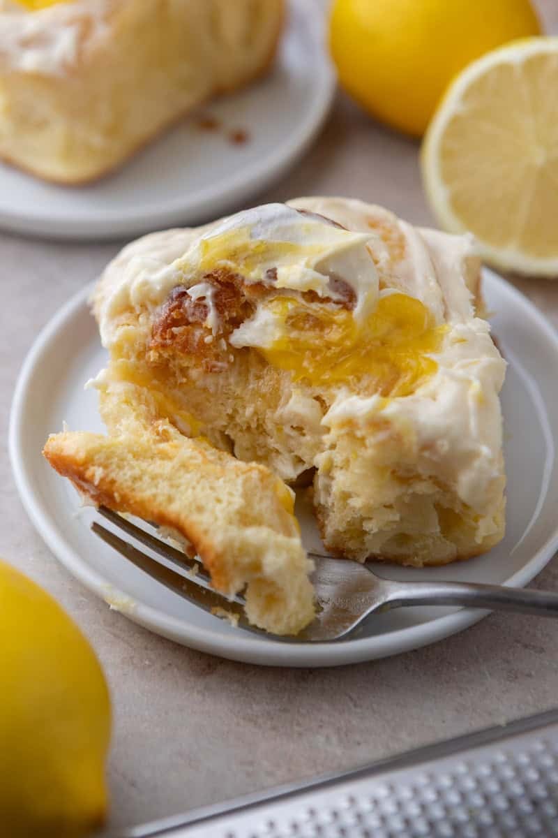 Lemon roll pulled apart on a white plate showing lemon curd pockets inside