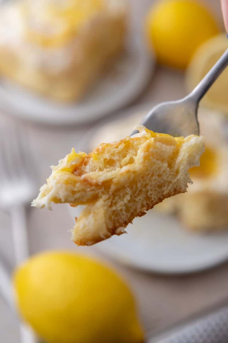 A forkful of lemon roll with lemon curd showing the soft fluffy texture inside