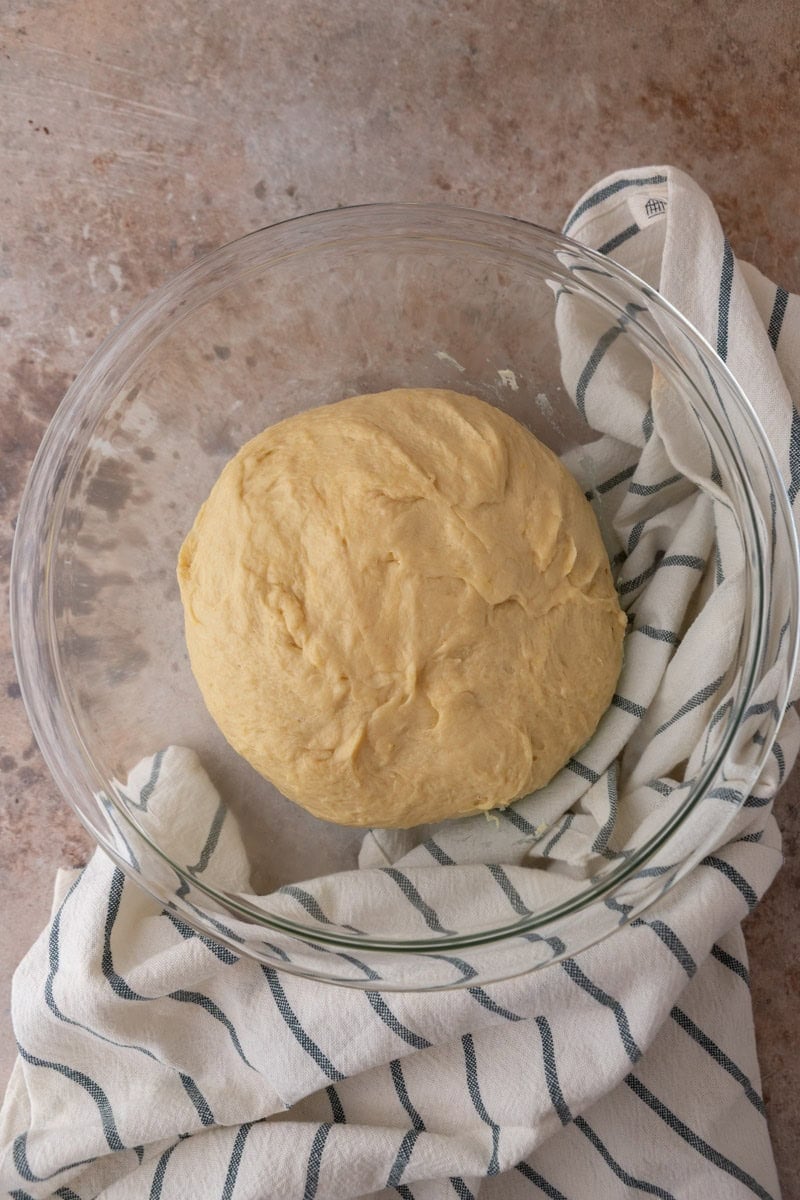 Smooth ball of lemon brioche dough in a glass bowl before first rise