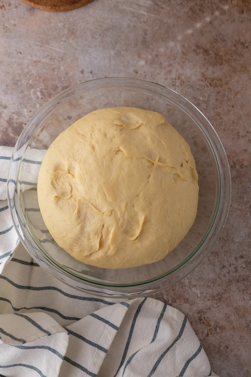 Doubled lemon brioche dough in a glass bowl after first rise